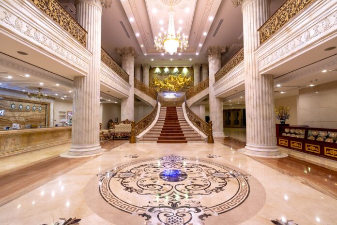Elegancki hall hotelowy z marmurową posadzką, schodami i żyrandolem
